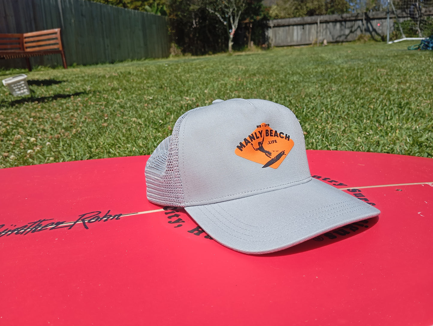 Grey trucker cap on surfboard.